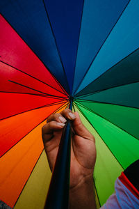 Close-up of hand holding multi colored umbrella