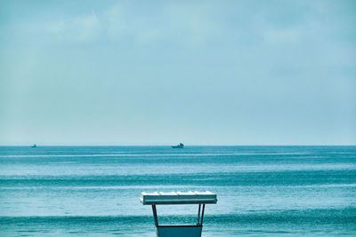 Empty chair on beach against sky