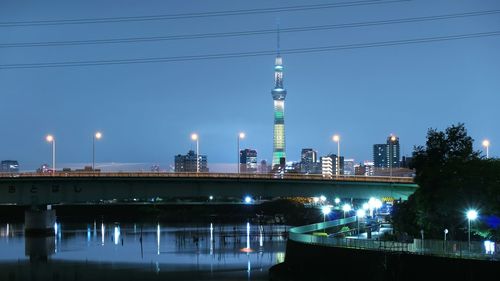 Bridge over river against illuminated tokyo sky tree at night