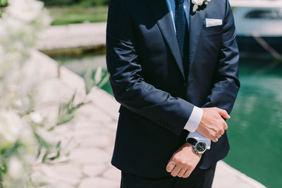 Midsection of man holding umbrella standing against blurred background