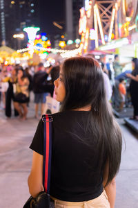 Rear view of woman sitting at amusement park at night