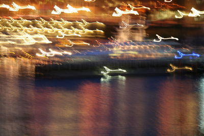 Light trails above blurred motion of boat at lake during night