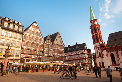 People on street against buildings in city