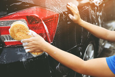 People worker man holding hand yellow sponge and bubble foam cleanser window for washing car.