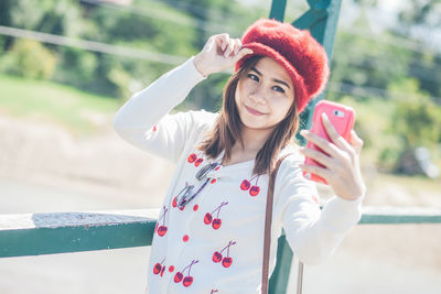 Woman taking selfie while standing against railing