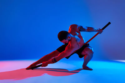 Full length of man exercising against colored background