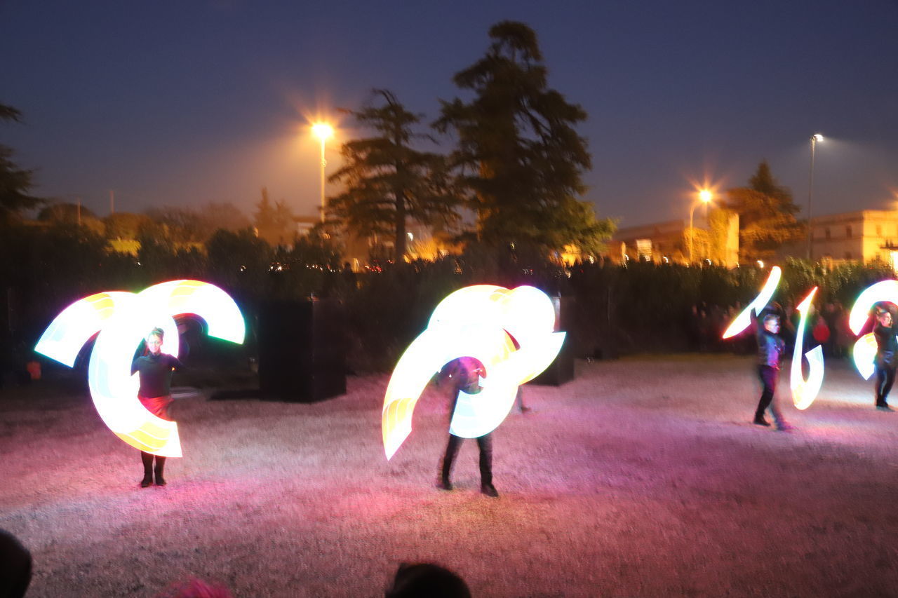 PEOPLE ON ILLUMINATED STREET AT NIGHT