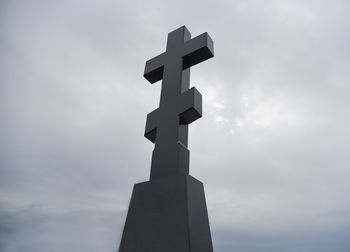 Low angle view of cross sculpture against sky