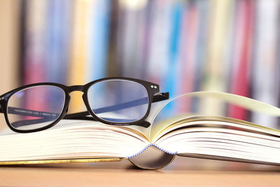 Close-up of eyeglasses with book on table
