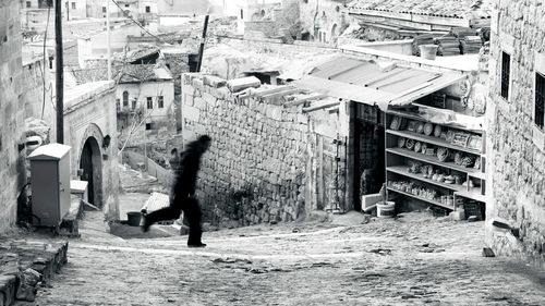 Side view of woman walking on street amidst buildings