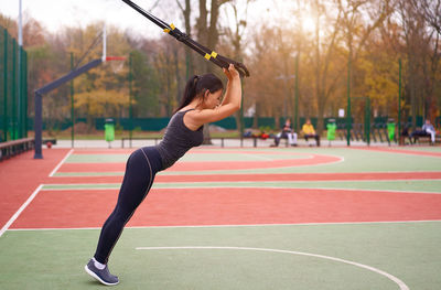 Full length of woman with arms raised against trees