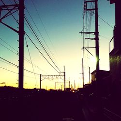Silhouette electricity pylon against sky during sunset