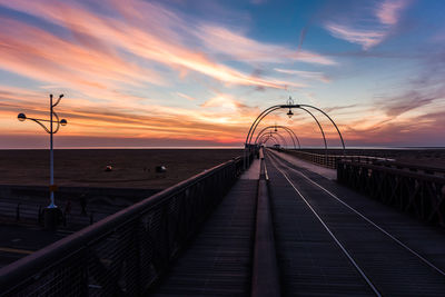 Southport pier over beach against sky during sunset