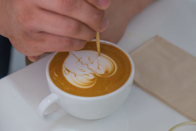 Cropped image of hand holding coffee cup on table