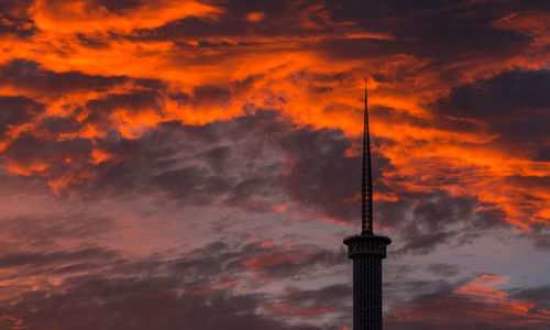 Low angle view of communications tower against cloudy sky during sunset