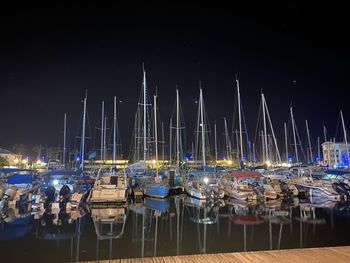 Sailboats moored in harbor at night