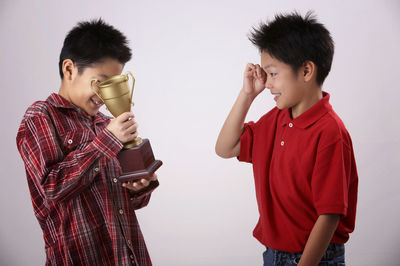 Boy with brother holding trophy against white background