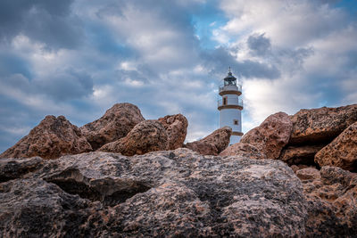 Low angle view of rocks and lighthouse against sky