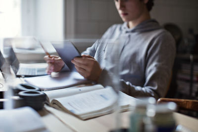 Teenage boy using digital tablet while studying at home