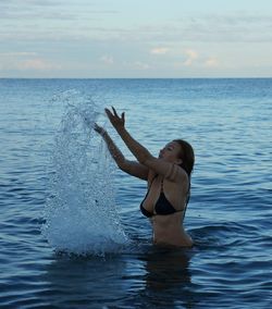 Woman in sea against sky