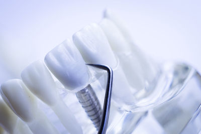 Close-up of dentures with medical equipment against white background