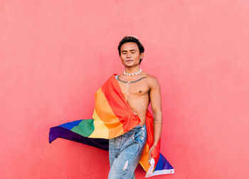 Portrait of young man standing against pink background