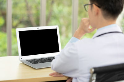 Man using mobile phone while sitting on table