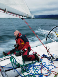 Man adjusting rigging on sailboat in iceland