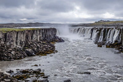 Scenic view of waterfall against sky