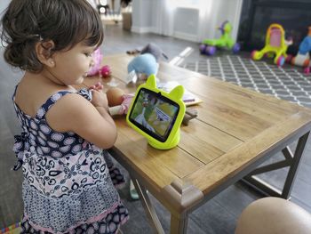 Cute girl looking at digital tablet sitting by table