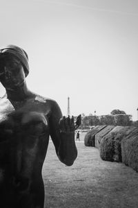 Statue of man holding sculpture against clear sky