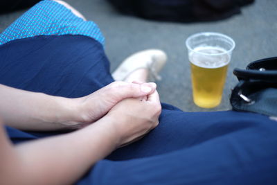 Cropped image of woman sitting by beer glass on floor