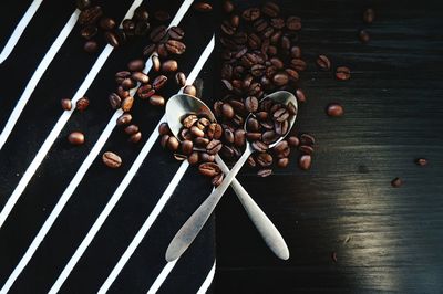 Directly above shot of spoons and roasted coffee beans on table