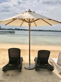 Chairs on beach by sea against sky