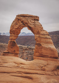 A man with a child is standing under delicate arch at arches np