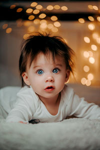 Portrait of cute baby girl on bed at home