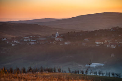 Houses on field against sky during sunset