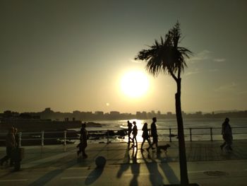 Silhouette people playing on beach against sky during sunset