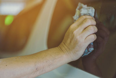 Cropped had of man cleaning car window