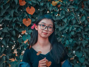 Portrait of smiling woman standing by leaves