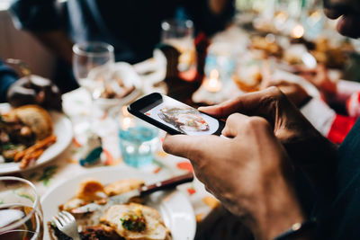 Midsection of man using mobile phone in restaurant