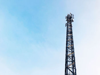 Telephone polls, cell towers on clear blue sky.