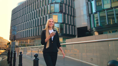 Portrait of young woman standing against buildings