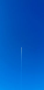 Low angle view of vapor trail against clear blue sky