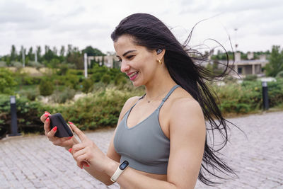 Smiling woman using mobile phone while standing outdoors
