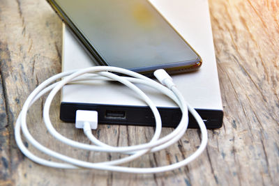 Close-up of mobile phone connected to portable charger on table