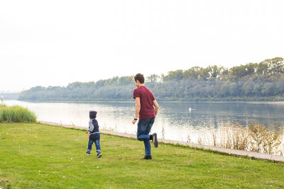 Full length of father and son on lake against plants