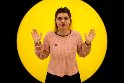 Portrait of teenage girl standing against yellow background