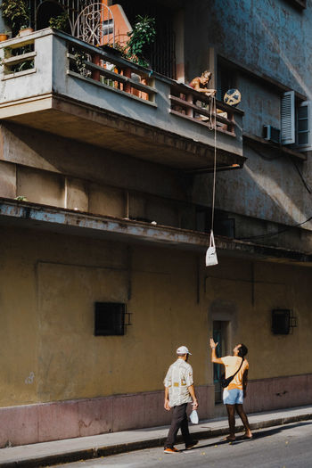 REAR VIEW OF PEOPLE WALKING ON STREET AGAINST BUILDINGS