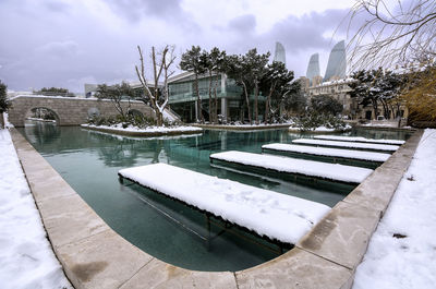 Swimming pool by river in city against sky